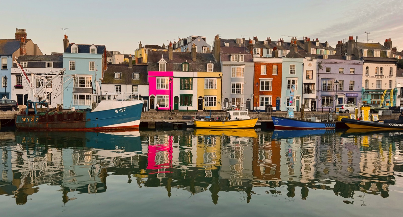 Colourful harbourside buildings and fishing boats reflected in Weymouth harbour