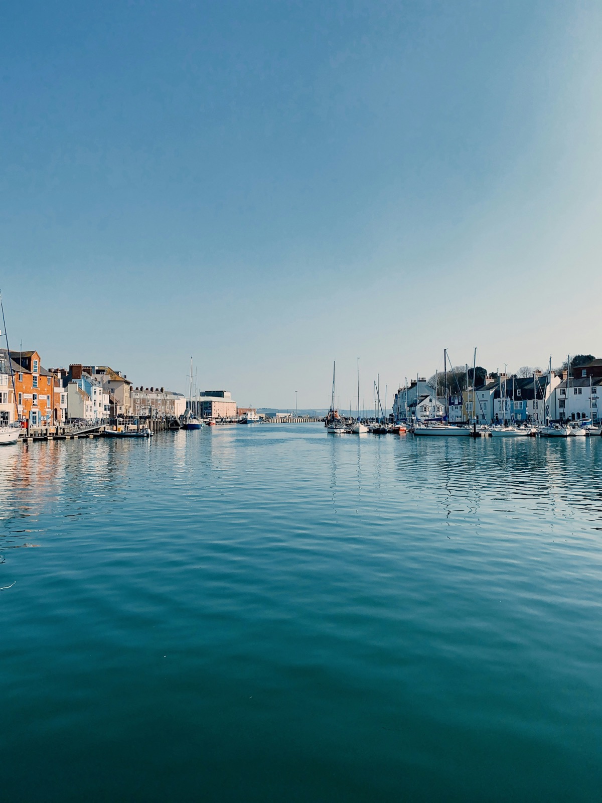 Weymouth harbour marina with calm blue water and sailing boats