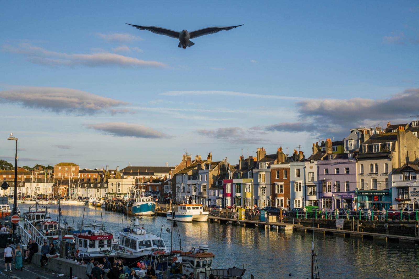 Weymouth harbour at sunset with colourful buildings and fishing boats