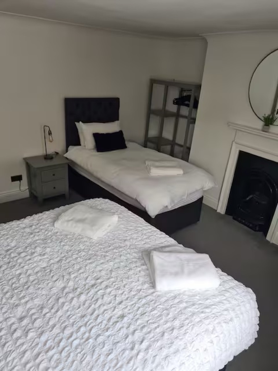 Twin bedroom with tufted headboards, fireplace and mirror at The Escape Weymouth