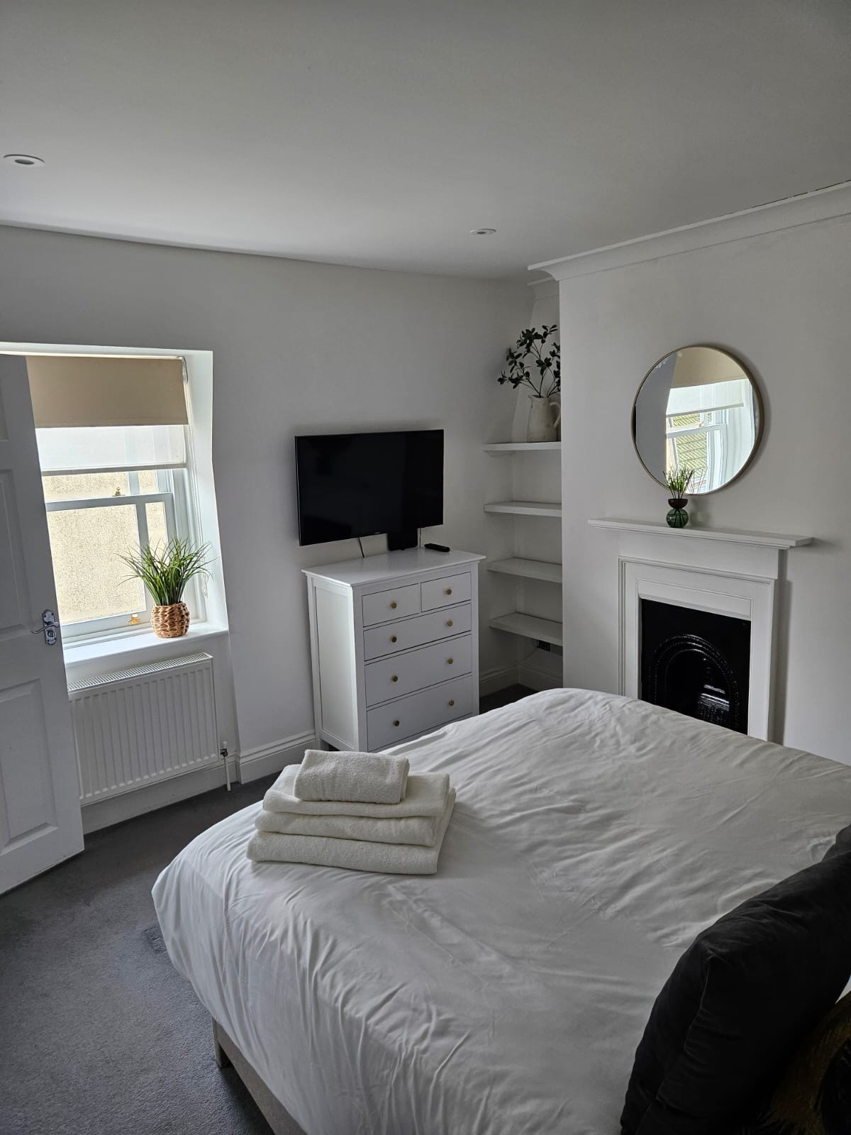 Second bedroom with tufted headboard and period window at The Escape